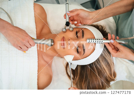 Many of different cosmetitian tools. Woman face getting facial care by beautician hands at spa salon Many of different cosmetitian tools. Woman face getting facial care by beautician hands at spa salon 127477178