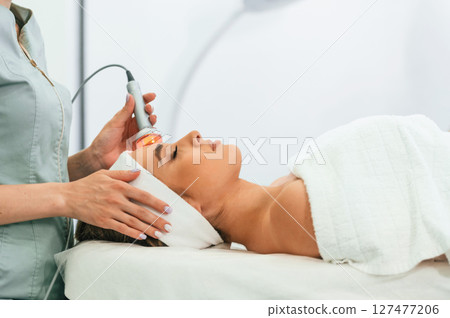 Apparatus for galvanization is used. Woman face getting facial care by beautician hands at spa salon 127477206