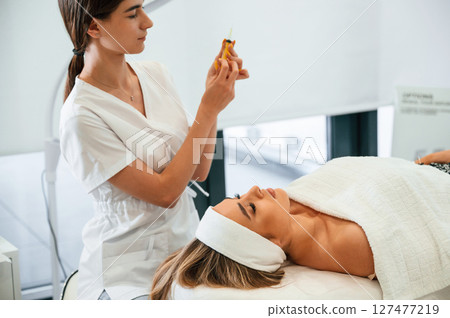 Getting ready for injection. Woman face getting facial care by beautician hands at spa salon 127477219