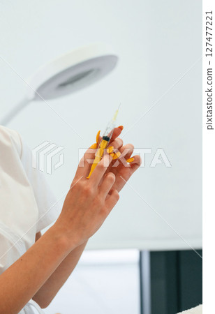 Close up view of beautician hands that is holding syringe Close up view of beautician hands that is holding syringe 127477221
