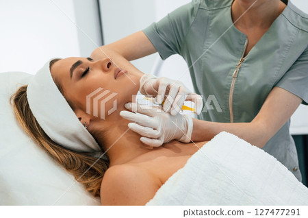 Making injection. Woman face getting facial care by beautician at spa salon Making injection. Woman face getting facial care by beautician at spa salon 127477291