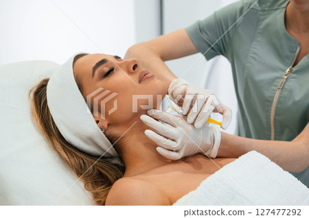 Making injection. Woman face getting facial care by beautician at spa salon Making injection. Woman face getting facial care by beautician at spa salon 127477292