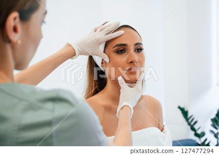 Checking final results. Woman face getting facial care by beautician at spa salon 127477294