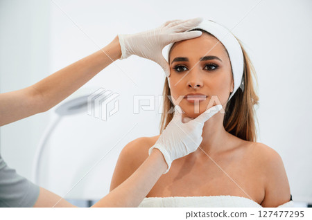 Checking final results. Woman face getting facial care by beautician at spa salon 127477295