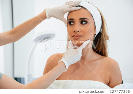 Checking final results. Woman face getting facial care by beautician at spa salon 127477296