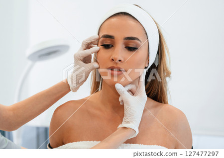 Woman face getting facial care by beautician at spa salon 127477297