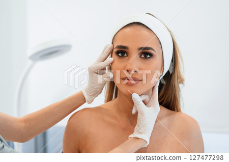Woman face getting facial care by beautician at spa salon 127477298