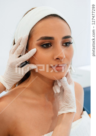 Woman face getting facial care by beautician at spa salon Woman face getting facial care by beautician at spa salon 127477299