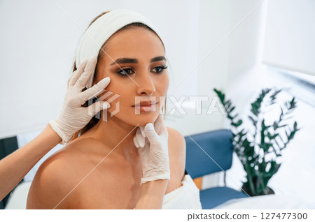 Woman face getting facial care by beautician at spa salon Woman face getting facial care by beautician at spa salon 127477300