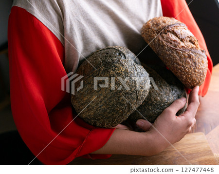 Woman hand hold fresh baked sourdough bread. Presenting Homemade ciabatta bread. 127477448