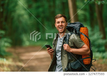 With smartphone in hands. Tourist in summer forest. Conception of exploration and leisure 127477593