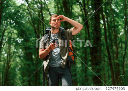 Searching the way, with smartphone for navigation. Tourist in summer forest. Conception of exploration and leisure Searching the way, with smartphone for navigation. Tourist in summer forest. Conception of exploration and leisure 127477603