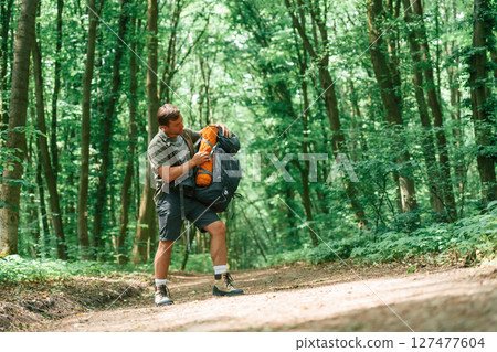 Opening the backpack. Tourist in summer forest. Conception of exploration and leisure 127477604