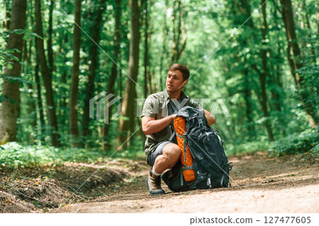 Opening the backpack. Tourist in summer forest. Conception of exploration and leisure 127477605