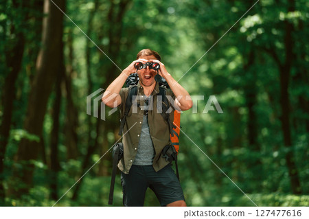 Looking through the binoculars. Tourist in summer forest. Conception of exploration and leisure 127477616