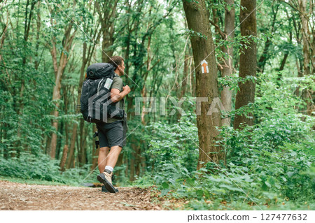 Mark with arrow on the tree that is showing the way. Tourist in summer forest. Conception of exploration and leisure 127477632