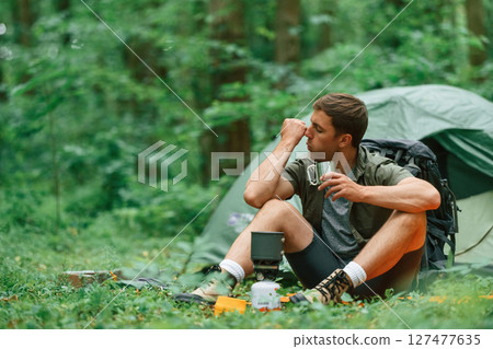 Boiling water, sitting near the tent. Tourist in summer forest. Conception of exploration and leisure 127477635