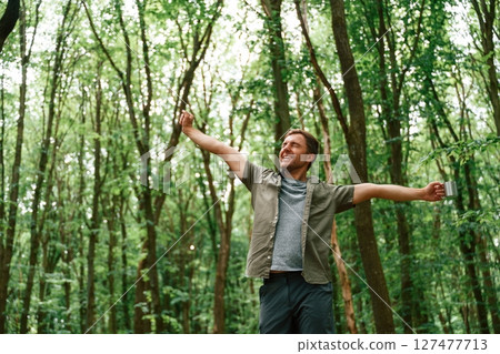 Enjoying the freedom, hands to the sides. Tourist in summer forest. Conception of exploration and leisure 127477713