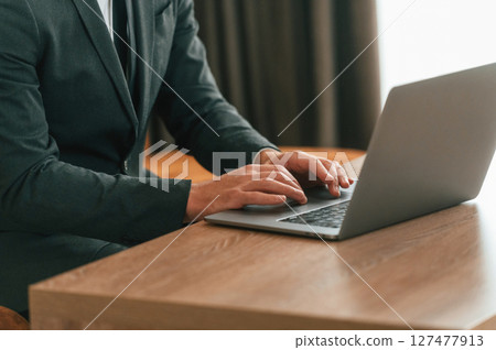 Close up view of businessman in suit and tie that is working by using laptop 127477913