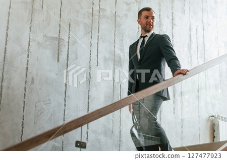 Man in business suit and tie with case in hands is on the stairs Man in business suit and tie with case in hands is on the stairs 127477923