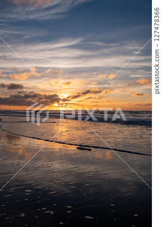 Witness the breathtaking beauty of a stunning sunset over calm ocean waves at the beach 127478366