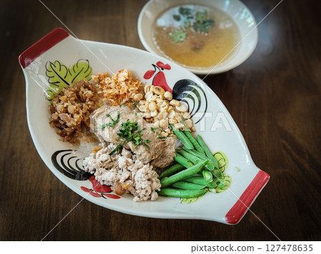 Thai Cha Kang Rao, a white noodle with minced pork, pork skin sliced yardlong bean with shredded culantro in chiecken pattern dish on wood table texture 127478635