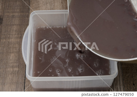 The process of making the summer Japanese sweet Mizu Yokan: Melting the agar and red bean paste and pouring it into a mold The process of making the summer Japanese sweet Mizu Yokan: Melting the agar and red bean paste and pouring it into a mold 127479050