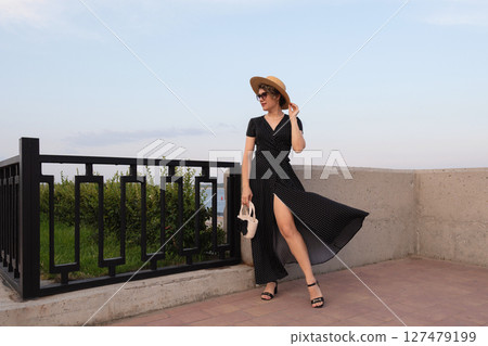 Wind lifts polka dot dress as woman poses by railing Wind lifts polka dot dress as woman poses by railing 127479199