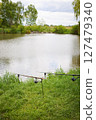 Two fishing rods stand ready by a calm lake, awaiting a peaceful day of angling 127479340