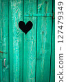 Rustic green wooden door with a heart-shaped cutout, showing weathered paint and charming detail 127479349