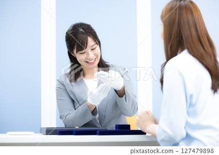 一位女士在採購公司的櫃檯評估一件商品 一位女士在採購公司的櫃檯評估一件商品 127479898