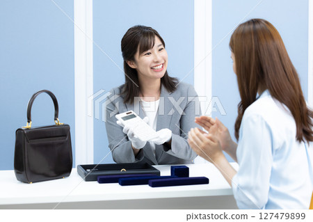 一位女士在採購公司的櫃檯評估一件商品 127479899