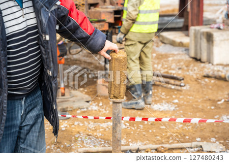 Man cutting and cleaning soil sample for laboratory analysis. Preparation of core material for geotechnical testing and scientific evaluatio 127480243