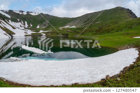Glacial lake in low clouds in changeable weather Glacial lake in low clouds in changeable weather 127480547