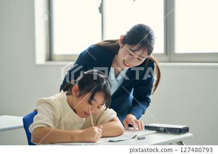 A teacher teaching children at a cram school 127480793