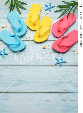 Colorful flip flops and starfish creating summer vacation atmosphere on wooden background 127480919
