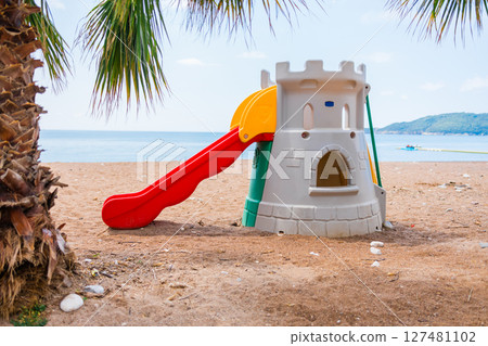 Colorful plastic playground with slides and castle structure on sand. Outdoor recreation, children's fun zone, and imaginative play environment concept. Colorful plastic playground with slides and castle structure on sand. Outdoor recreation, children's fun zone, and imaginative play environment concept. 127481102
