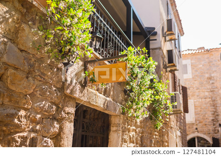 Blank signboard on stone building wall in Mediterranean alley. Concept of urban signage, empty brand space, and local European architecture. Copy space 127481104