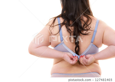 Woman back view putting on her bra lingerie. 127481403