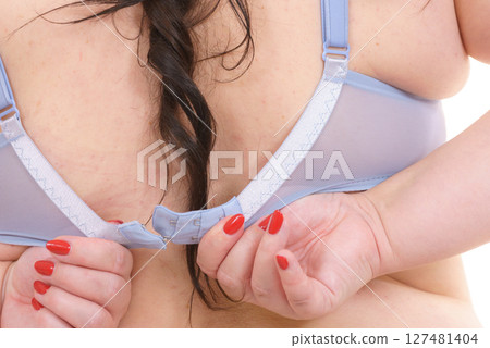 Woman back view putting on her bra lingerie. 127481404