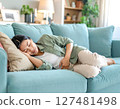 A woman feeling unwell due to menstrual cramps resting on a sofa 127481498