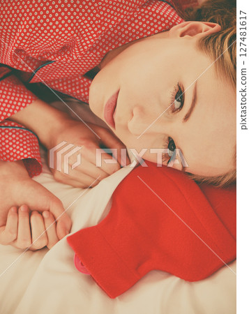 Woman sleeping with warm red hot water bottle Woman sleeping with warm red hot water bottle 127481617