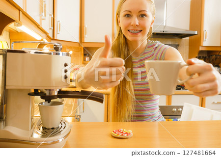 Woman in kitchen making coffee from machine 127481664