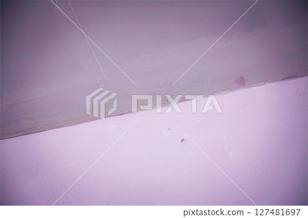 Close-up of a damaged purple painted wall and ceiling corner 127481697