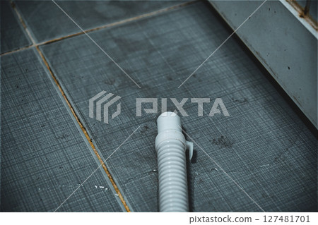 White plastic pipe on a tiled dark floor White plastic pipe on a tiled dark floor 127481701