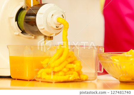 Making orange juice in juicer machine in kitchen 127481740