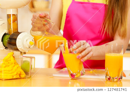 Woman pouring orange juice drink in glass 127481741