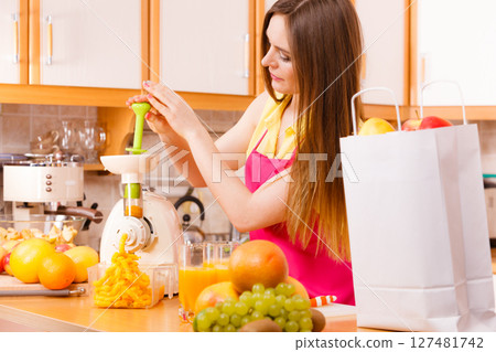 Woman making orange juice in juicer machine 127481742