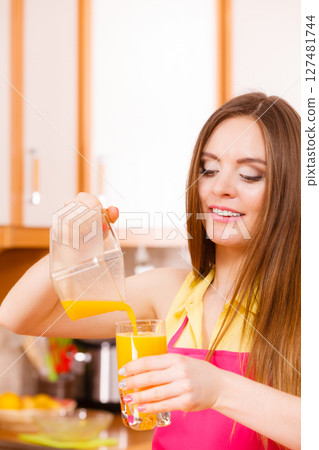 Woman make orange juice in juicer machine pouring drink in glass 127481744