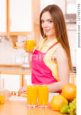 Woman in kitchen drinking fresh orange juice 127481748